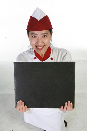 A female patissier holding an empty black board to the upの写真素材