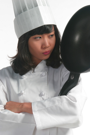 Close up shot of a female cook staring at a frying pan as arms crossedの写真素材