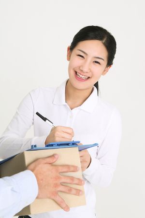 A female recipient signing on the sheet with toothy smileの写真素材