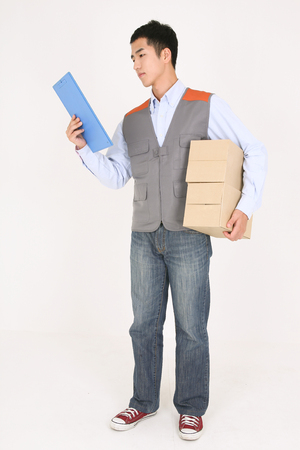 A delivery man checking the chart as holding boxes of shipments in armの写真素材
