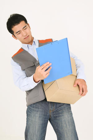A delivery man checking the chart as holding boxes of shipments in armの写真素材