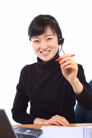 A female telemarketer holding a red pen as responding to the customerの写真素材