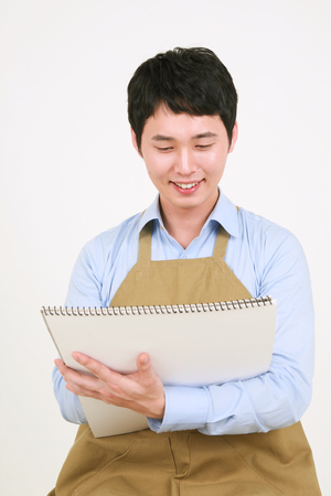 Close up shot of a male artist drawing on a sketchbook as holding it in armsの写真素材
