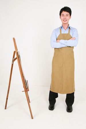 A male artist standing in front of the easel as crossing armsの写真素材