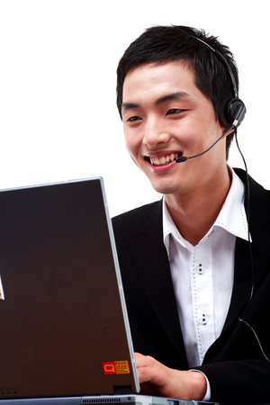 Close up shot of a male telemarketer typing on a laptop while responding to the customer on the headsetの写真素材