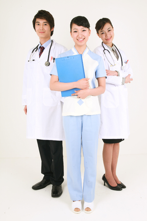 Full shot of A female nurse holding a patient chart as standing between a male doctor and a female doctorの写真素材
