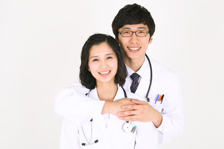 A male doctor putting arms around the neck of a female doctorの写真素材