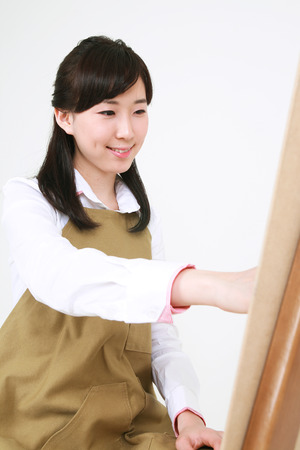A female artist drawing with a pencil sitting in front of the easelの写真素材