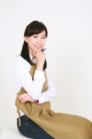 A female artist thinking deeply as putting a pencil-holding-hand on the chinの写真素材