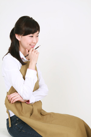 A female artist thinking deeply as putting a pencil-holding-hand on the chinの写真素材