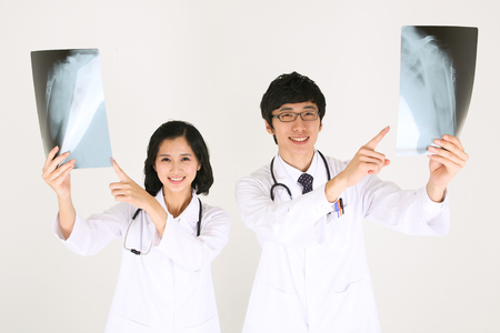 A couple of doctors looking at x-ray photographs as pointingの写真素材