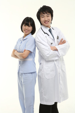 A male doctor and a female nurse standing against each other's back as crossing armsの写真素材
