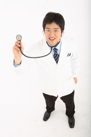 Full shot of A male doctor pretending to apply the stethoscope in the air with a toothy smileの写真素材