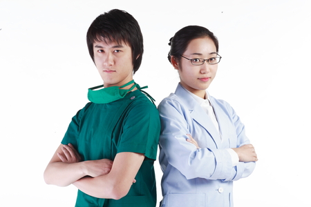 Close up shot of A male doctor and a female doctor standing against each other's back as crossing armsの写真素材