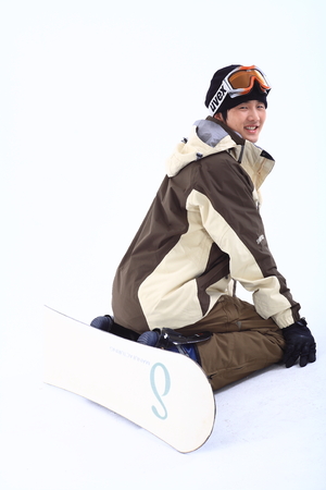 Front shot of A male snowboarder putting ski goggles on forehead falling on knees in painの写真素材