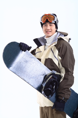 A male snowboarder putting ski goggles on forehead holding a snowboard in armsのeditorial素材