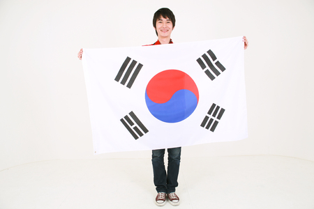 Full shot of A male Korean holding the national flag of Korea in front of himselfの写真素材