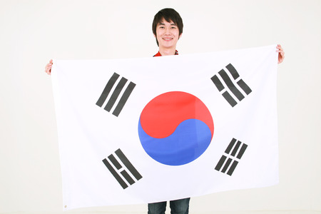 Close up shot of A male Korean holding the national flag of Korea in front of himselfの写真素材