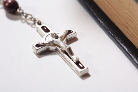 Isolated shot of rosary cross laid next to the bible