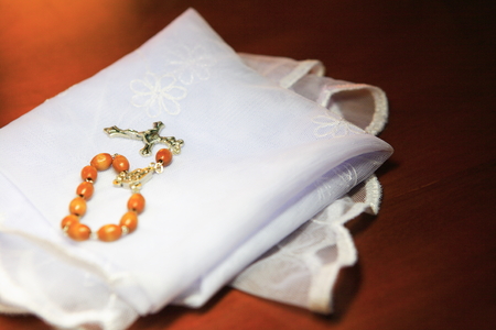 Close up shot of a brown rosary laid on the folded white mass veilの写真素材