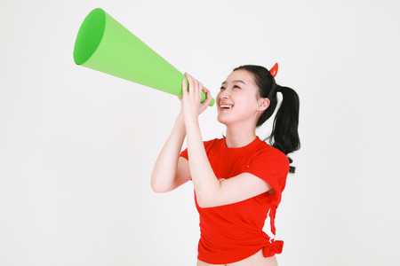 A Korean female soccer supporter with two ponytails posing with a cheering horn in studioの写真素材