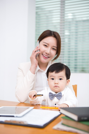 Working mom with the baby answering the phone at workの写真素材