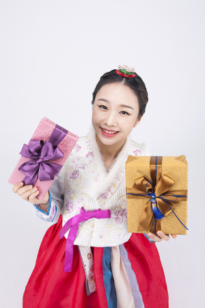 Young Asian woman in Hanbok, Korean traditional clothes, posing with gift boxes - isolated on whiteの写真素材