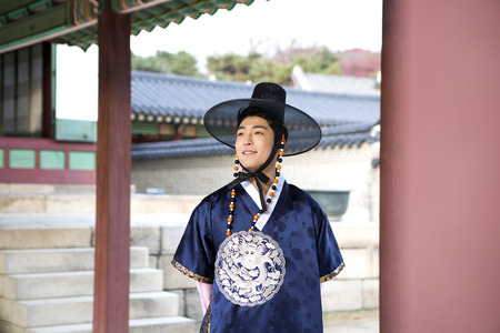 Young Asian man in Hanbok, Korean traditional clothes posing in Hanok, Korean traditional houseの写真素材