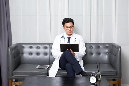 Asian male psychologist - reading as sitting down on long chairの写真素材