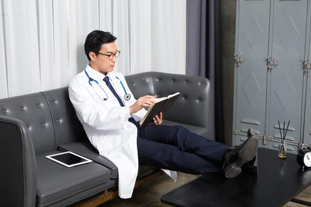 Asian male psychologist - reading as sitting down on long chairの写真素材