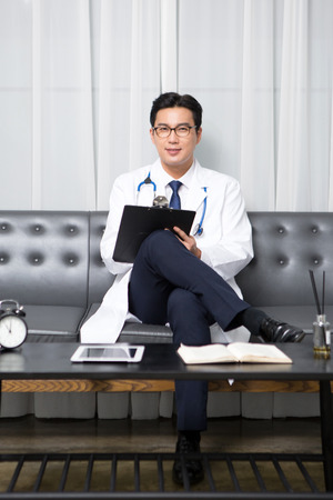 Asian male psychologist - reading as sitting down on long chairの写真素材