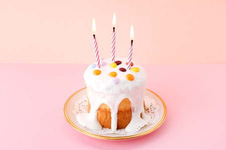 Sweet desserts - Mini round cake with lit candles in pink backgroundの写真素材