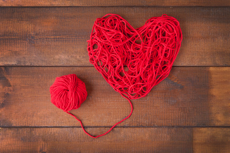 Red color knitting wool balls and thread heartの写真素材