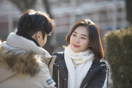 Asian couple dating at park - sitting on bench as facing each other at parkの写真素材