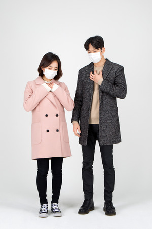 Asian couple isolated in white studio - posing as wearing winter wool coatsの写真素材