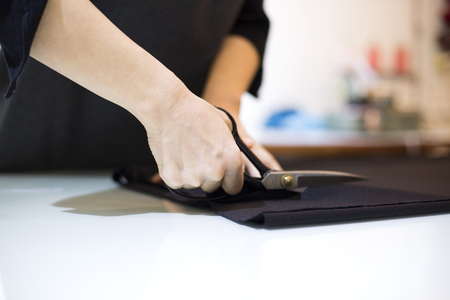 Isolated shot of a tailor's hands cutting fabric with scissorsの写真素材