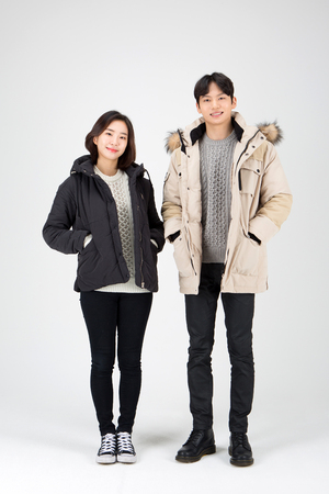 Asian couple isolated in white studio - posing as wearing winter padded coatsの写真素材