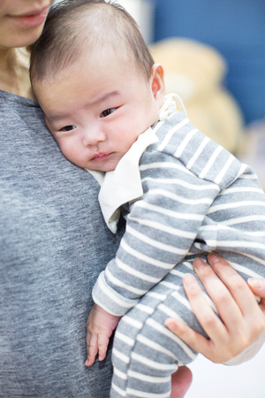 Baby studio photoshoot - Asian baby/infant being held in mother's armsの写真素材