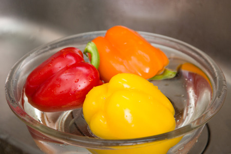 Close up shot of colorful paprikas in a bowl of waterの写真素材