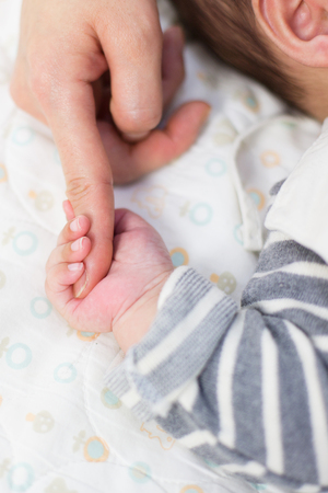 Baby studio photoshooting - Isolated shot of Asian baby/infant's hand holding mother's fingerの写真素材