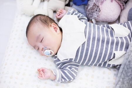 A studio photoshoot of an asian baby/infant sleeping in bedの写真素材