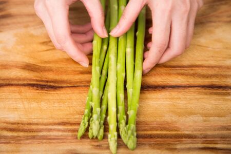 Isolated shot of cook's hands prepparing fresh ingredients - Green asparagusの写真素材