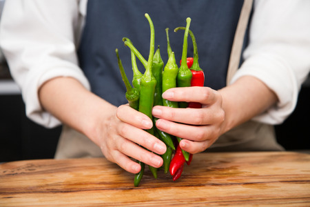 Isolated shot of cook's hands prepparing fresh ingredients - Gree peppers/Red peppersの写真素材
