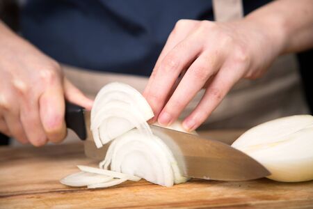 Isolated shot of cook's hands prepparing fresh ingredients - White onionsの写真素材
