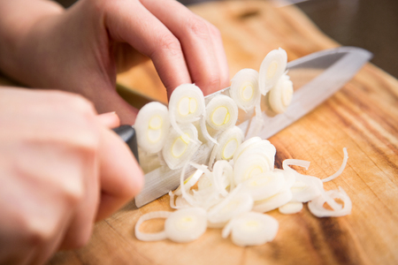 Isolated shot of cook's hands prepparing fresh ingredients - Green onions/Spring onionsの写真素材