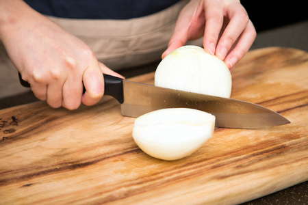 Isolated shot of cook's hands prepparing fresh ingredients - White onionsの写真素材