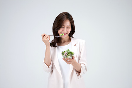 Isolated shot in studio - Asian career woman posing with fresh vegetables/greensの写真素材