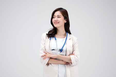 Isolated shot in studio - Asian career woman in white dress posing with a stethoscopeの写真素材