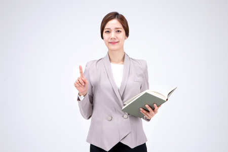 Isolated shot in studio - Asian career woman posing with a bookの写真素材