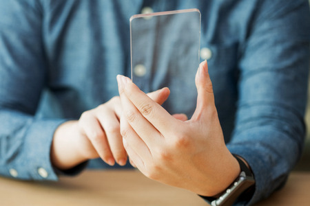 Isolated shot of hands holding/grabbing and operating/using transparent smart phoneの写真素材